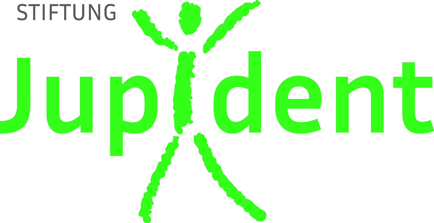 Eine Frau und ein Mädchen sitzen auf dem Boden und spielen lächelnd mit einem Spielzeug in einem hellen Raum. @Stiftung Jupident