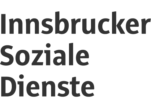 Eckansicht eines mehrstöckigen Gebäudes in heller Farbe mit Fenstern und Autos davor.