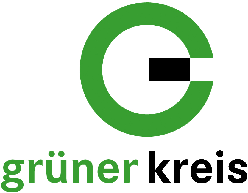 Moderne, mehrstöckige Gebäude mit großen Fenstern, umgeben von Bäumen und einem gepflegten Grünbereich.
