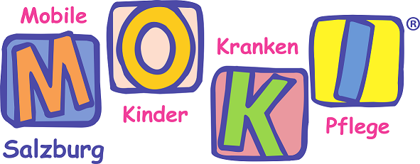 Zwei fröhliche Kinder liegen auf der Wiese, einer hält ein Spielzeug in der Hand und lächelt in die Kamera.