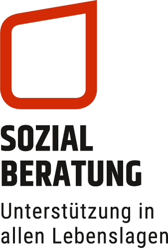 Zwei Frauen unterhalten sich am Schreibtisch, hinter einer Trennwand, mit viel Tageslicht und Pflanzen im Hintergrund.